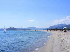 - une plage avec des personnes et un voilier dans l'eau dans l'établissement Rotonda Sul Mare, à Budoni