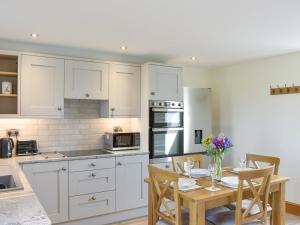 Una cocina con gabinetes blancos y una mesa con sillas. en Deer Park Barn - Uk33323, en Reeth