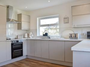 a kitchen with white cabinets and a window at Loanmhor in Kilmory +16 photos