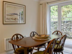 a dining room with a table and chairs and a window at Meadowcroft Cottage in Bowness-on-Windermere