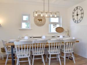 a dining room table with white chairs and a clock at Loanmhor in Kilmory