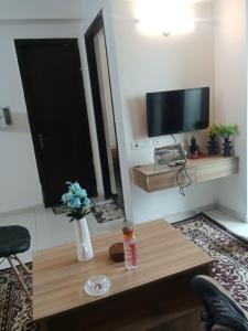 un soggiorno con un tavolo e una TV di Sunworld Arista T10 ,906 a Noida