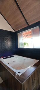 a large bath tub in a room with a window at Chalé Montanhez hidromassagem piscina in Caparaó Velho
