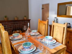 un tavolo con piatti, bicchieri e una bottiglia di vino di Daisy Cottage a Sea Palling