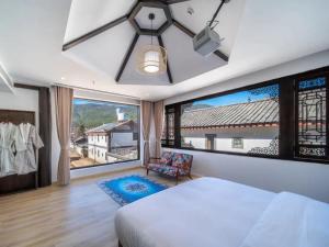 een slaapkamer met een bed en een groot raam bij Dawnscape snowmountain viewing Courtyard - Baisha old town in Lijiang