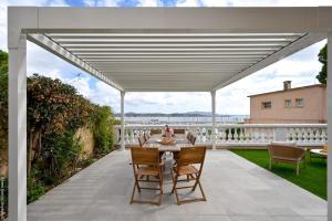 a white pergola on a patio with a table and chairs at Jonaxel - Sur le port de Bandol in Bandol +33 photos