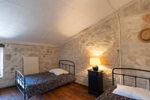 a bedroom with two beds in a room with stone walls at Bellevue De La Maréchale in Orgnac-lʼAven +15 photos