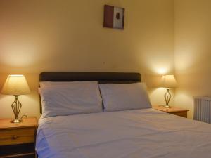 a bedroom with a bed with white sheets and two lamps at Atlantic Lodge in Saint Columb Major