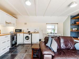 a living room with a couch and a kitchen at Studio Cottage in Treffynnon 