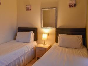 a bedroom with two beds and a lamp on a night stand at Atlantic Lodge in Saint Columb Major +2 photos