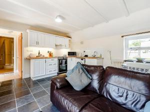 a living room with a leather couch in a kitchen at Studio Cottage in Treffynnon 