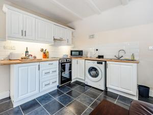 a kitchen with white cabinets and a washer and dryer at Studio Cottage in Treffynnon  +9 photos