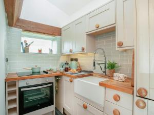 a kitchen with white cabinets and a sink at Welcome Cottage in Woolfardisworthy +17 photos
