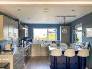 a kitchen with blue walls and white cabinets at Villa Calafia - Uk38491 in Porthtowan