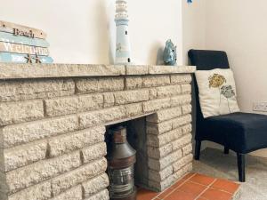 ein Wohnzimmer mit einem gemauerten Kamin mit einem Stuhl in der Unterkunft Dolphin Cottage in Braunton