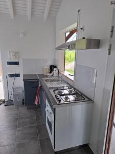 a white kitchen with a stove and a sink at Bungalow AN KAN LA in Capesterre