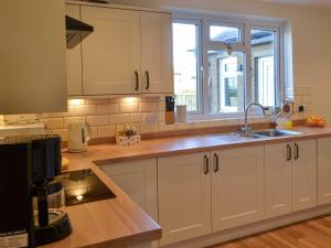 a kitchen with white cabinets and a sink at Low Chibburn Farm Cottage in Hadston +17 photos