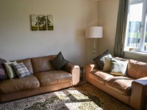 a living room with two brown leather couches at Low Chibburn Farm Cottage in Hadston