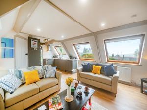 a living room with two couches and a kitchen at The Loft in Yealmpton