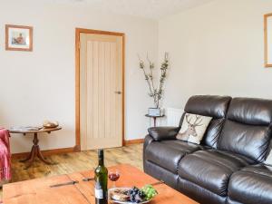 ein Wohnzimmer mit einer Ledercouch und einem Tisch in der Unterkunft High Threave Cottage in Kirkcowan