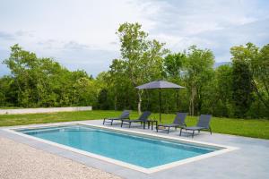 a swimming pool with two chairs and an umbrella at Wunderschöner Neubau Bungalow Mit Privatem Pool Und Jacuzzi in Vozilići