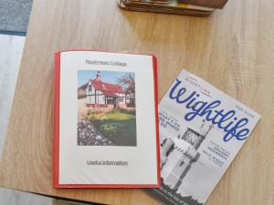 two books sitting on a table next to a house at Rookmead Cottage in Yarmouth