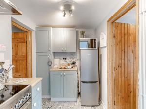 eine Küche mit blauen Schränken und einem Kühlschrank in der Unterkunft Crompton Cottage in Bretforton