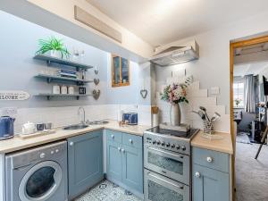 eine Küche mit blauen Schränken und einer Waschmaschine und einem Trockner in der Unterkunft Crompton Cottage in Bretforton