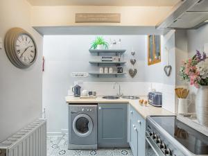 eine Küche mit einer Waschmaschine und einer Uhr an der Wand in der Unterkunft Crompton Cottage in Bretforton