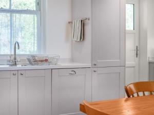 a kitchen with white cabinets and a wooden table at Bessborough in Saint Mawes