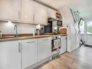 a kitchen with white cabinets and a wooden floor at Uk41506 - Sunnybank in Hodgeston
