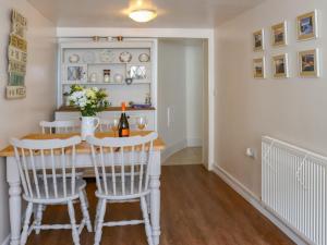 Un comedor con una mesa y sillas blancas. en Chapel Street Cottage, en Amlwch