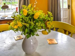 eine weiße Vase mit gelben Blumen auf dem Tisch in der Unterkunft The Old Bakehouse in Perranporth