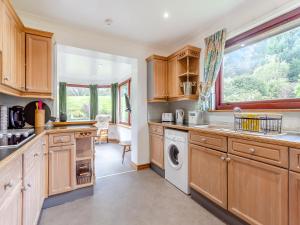 a kitchen with wooden cabinets and a washer and dryer at Drummond House Uk42979 in Brackley