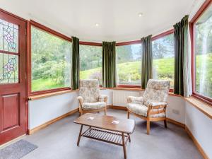 a living room with two chairs and a table and windows at Drummond House Uk42979 in Brackley +4 photos