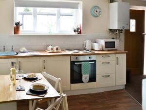 a kitchen with a table and a stove top oven at Cygnet Cottage - Uk43546 in Belford