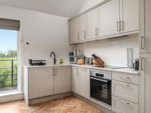 eine weiße Küche mit weißen Schränken und einem Fenster in der Unterkunft Uk47693 - Piglet Cottage in Wimbish + 12 Fotos