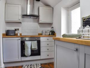 a kitchen with white cabinets and a stove at Quay Cottage in Bewdley
