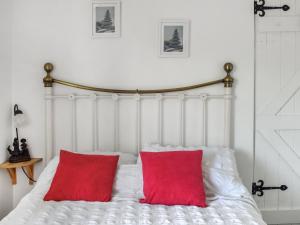 a white bed with two red pillows on it at Quay Cottage in Bewdley