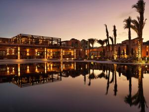 a building with a reflection in the water at dusk at The Chedi El Gouna in Hurghada
