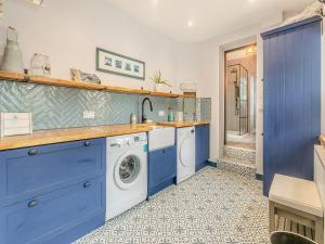 a kitchen with blue cabinets and a washer and dryer at Lanner Moon in Carnbrea +16 photos