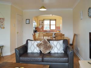 a living room with a leather couch and a kitchen at Ty Celyn in Broad Haven