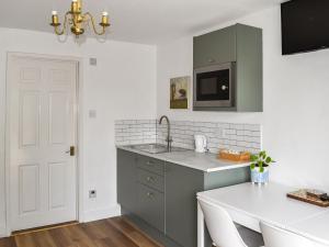 una cocina con armarios verdes y una mesa blanca en Little Fishes, en Ryde