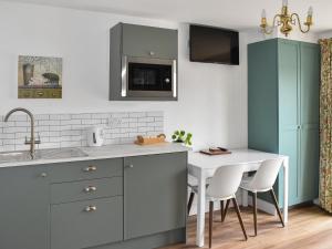 Una cocina con gabinetes azules y una mesa blanca. en Little Fishes, en Ryde