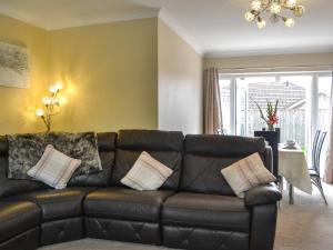 a living room with a black leather couch with pillows at Oceans 44 in Sewerby