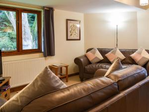 a living room with a leather couch and a window at Cysgod Y Coed in Llanbedr