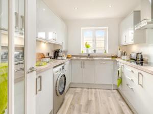 a kitchen with white cabinets and a washer and dryer at Blue Skies in Carew +26 photos