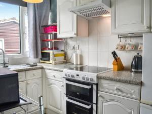 a kitchen with white cabinets and a stove top oven at Yeolde Woodern Country View Seashak - Uk46596 in Bridlington