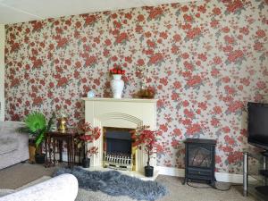 a living room with a fireplace and floral wallpaper at Yeolde Woodern Country View Seashak - Uk46596 in Bridlington