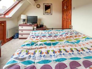 a bedroom with a bed with a colorful comforter at Chapel Court Loft Apartment in Beaumaris